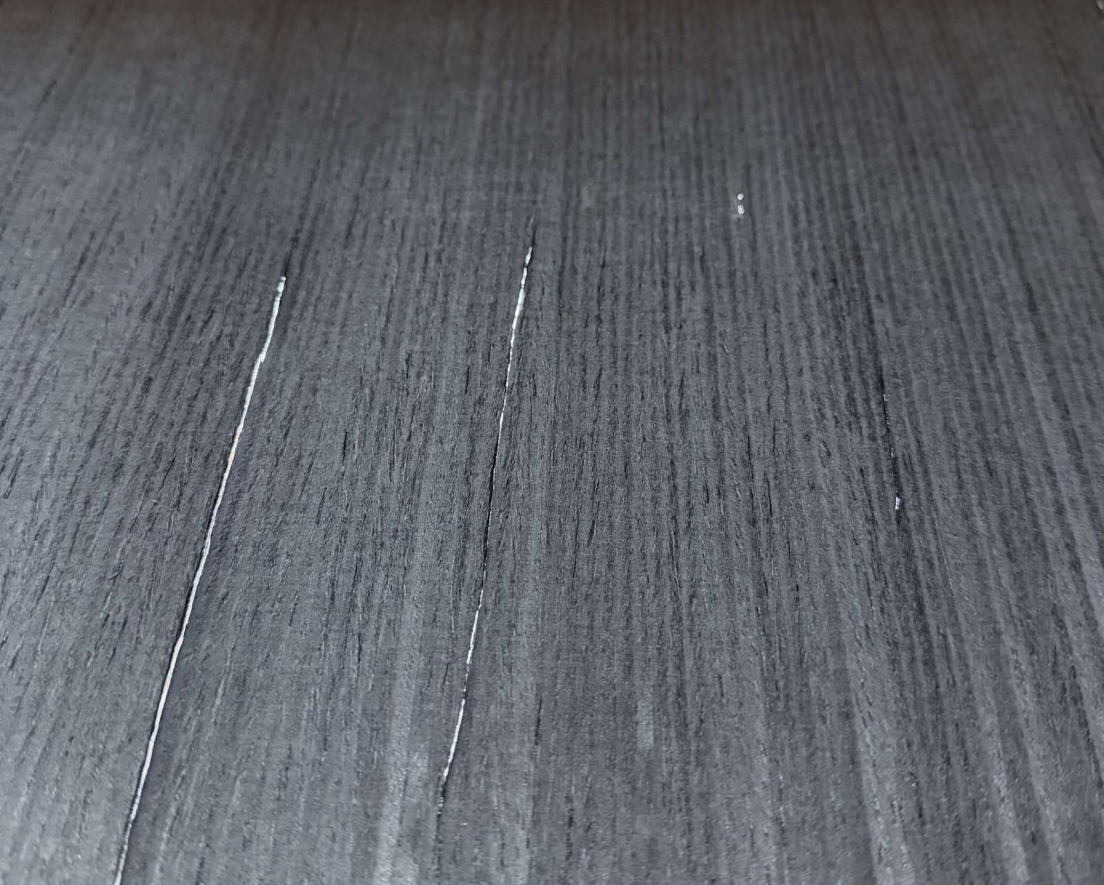 Hairline splits in wood veneer revealed by holding the sheet up to light